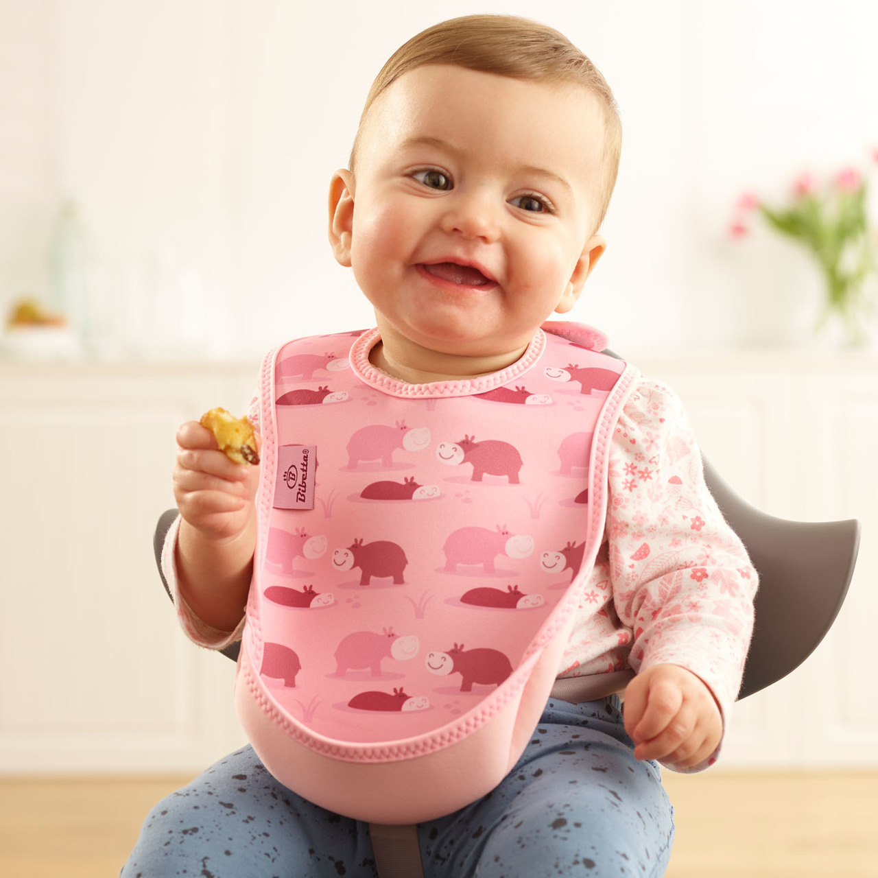 Baby wearing a Bibetta neoprene Ultrabib baby and child's bib with fold forwardpelican pocket in pink Hippos print