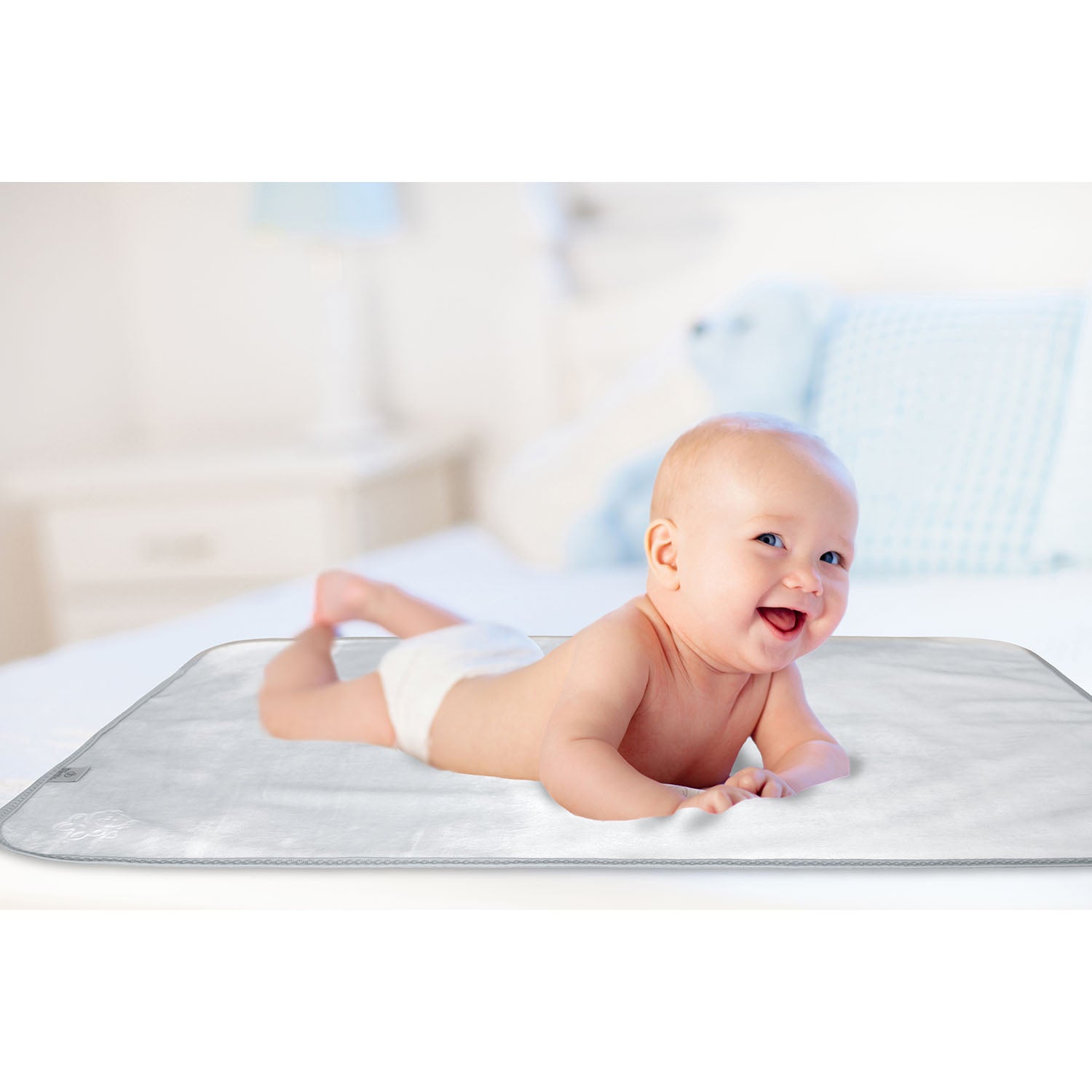 Happy baby lying on tummy on a soft waterproof Bibetta Plush tummy time mat in white and grey