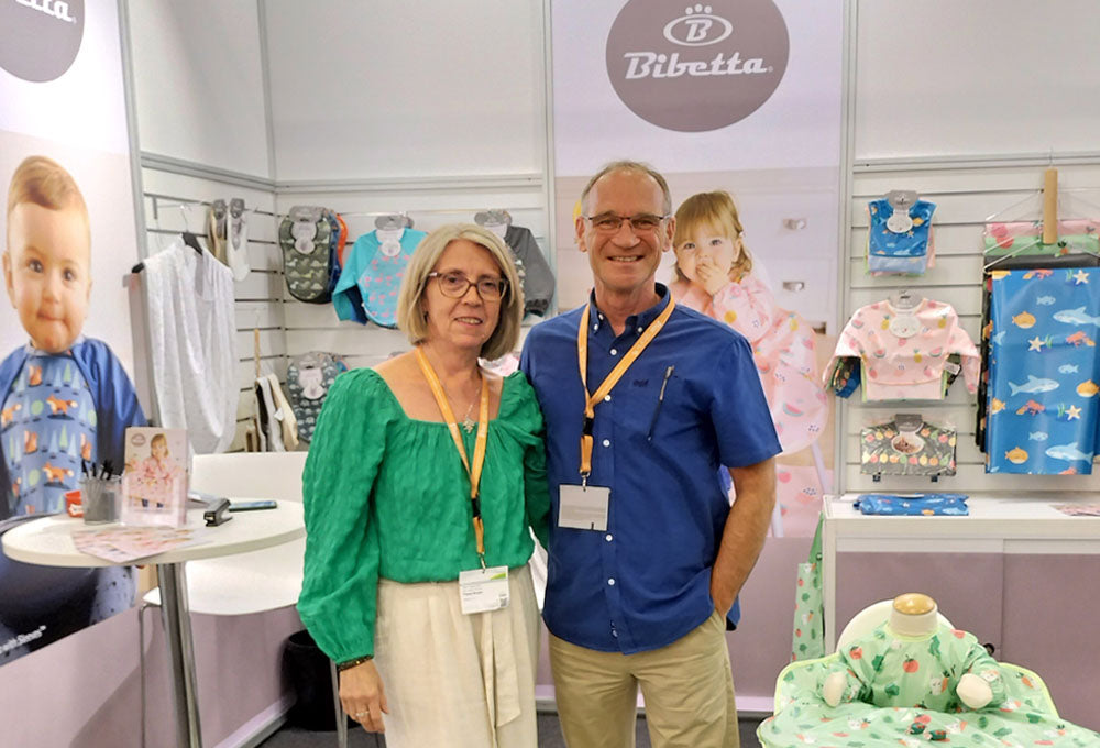 Bibetta Founders Paul and Fiona Brown at trade show exhibiting their Bibetta collection of products on the walls behind them.