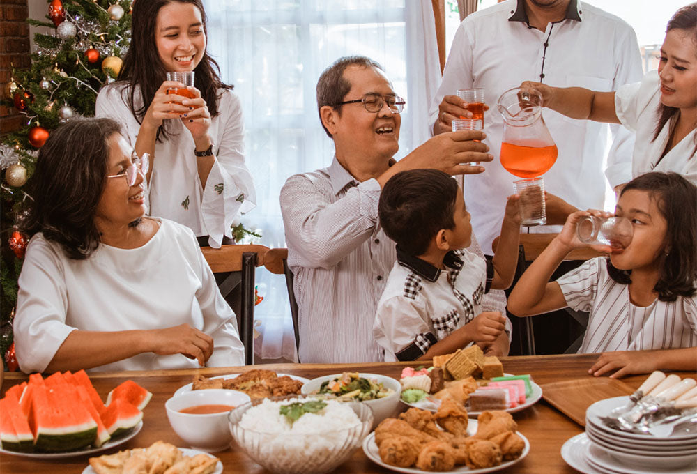 A family of multiple generations sitting around a table ready to eat a meal together.