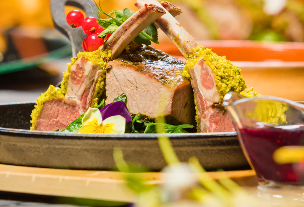 Dish of lamb with trimmings around it on a plate