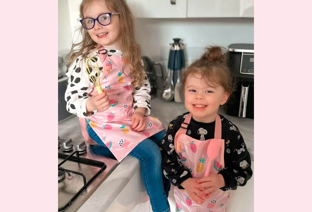 Two happy children wearing Bibetta Wipeezee pink aprons