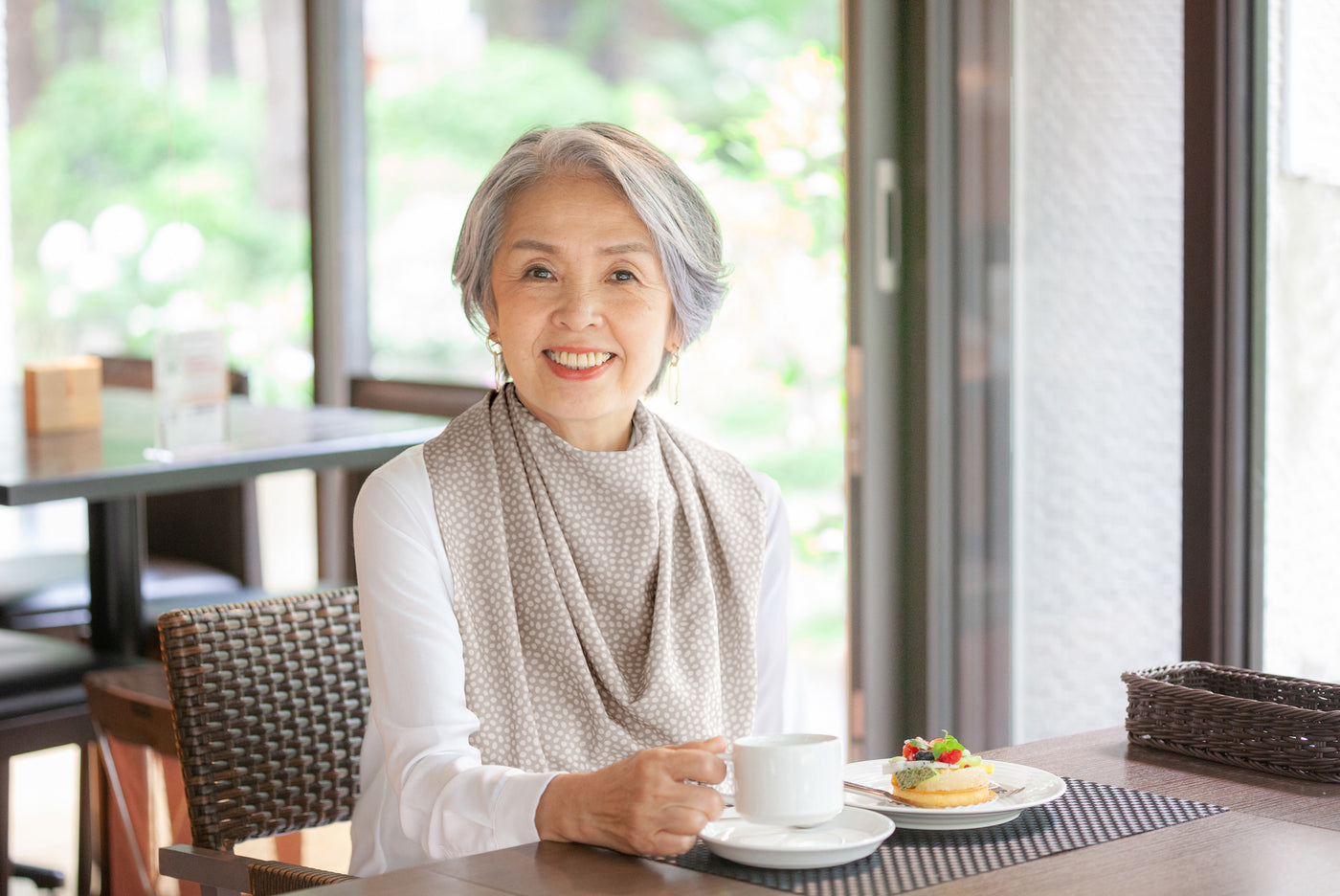 Elderly woman wearing a Care Designs Pashmina Scarf Style Clothing Protector adult bib whilst eating at the table- photo courtesy of Knot2 Japan