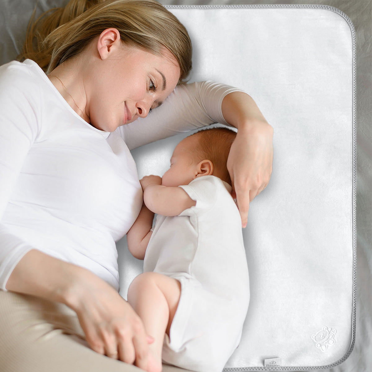 mother and baby both wearing white tops lying next to each other on a Bibetta Plush tummy time mat in cream and beige