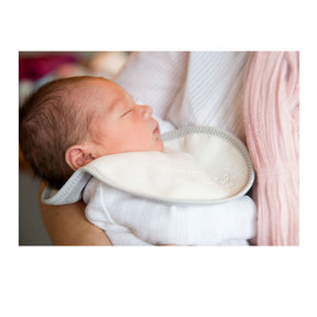 baby in a white sleepsuit wearing a bibetta white and grey plush newborn bib with a teddy embossed into the front of the bib. The baby is being held by their mum.