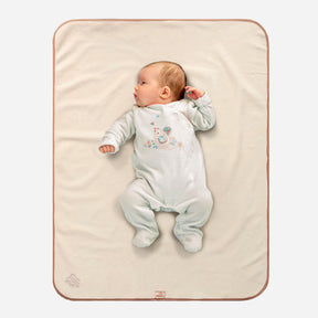 baby in white sleepsuit with mouse on the front lying on a Bibetta Cream and Beige plush tummy time mat