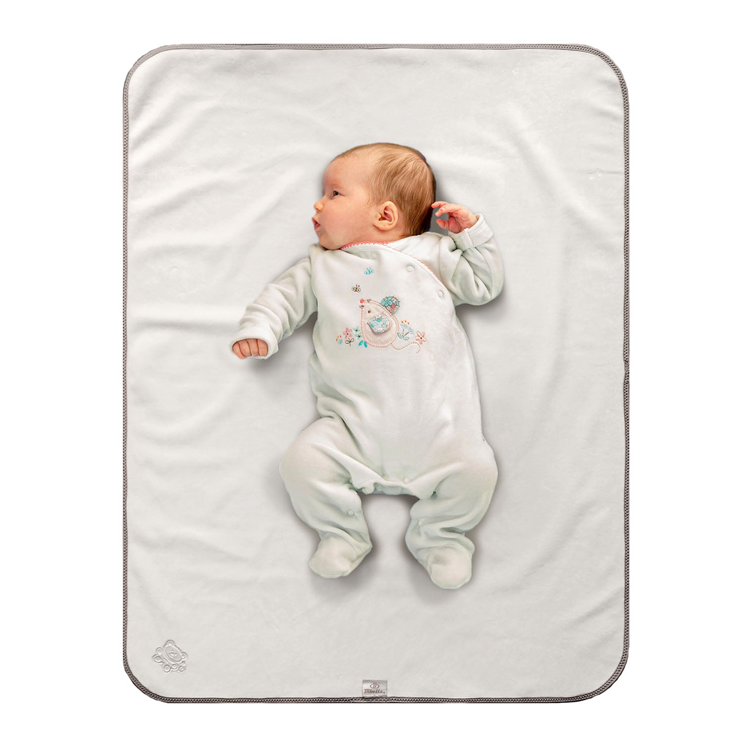 Baby in white sleep suit with bird motif on the front of it lying on a Bibetta cream and beige tummy time mat