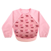 Bibetta pink baby bib with sleeves with hippo pattern, made of neoprene material, with the pocket flipped out to the front