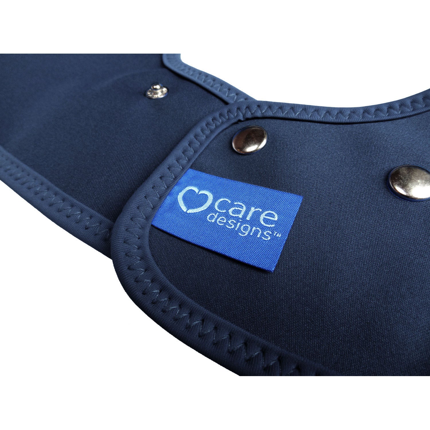 Close-up of the back of a navy Care Designs tabard bib with silver metal snaps and a blue brand label reading 'care designs'.