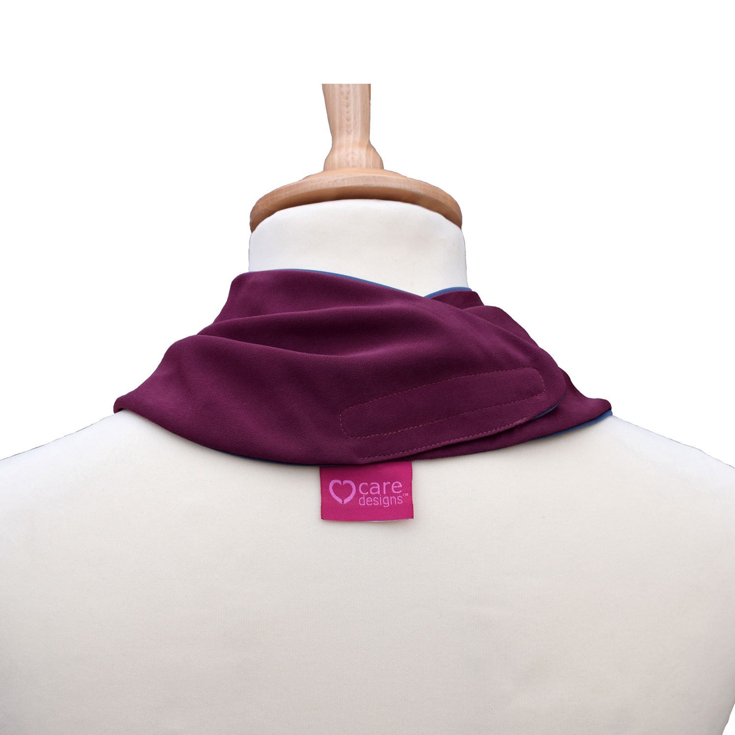 Back view of an aubergine neckerchief bib on a mannequin with 'care designs' label