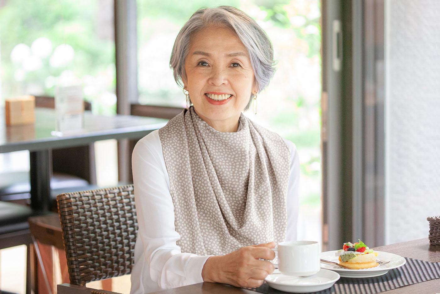 Senior woman wearing a stylish and dignified Care Designs Pashmina Scarf Style Clothing Protector adult bib whilst eating at the table- photo courtesy of Knot2 Japan