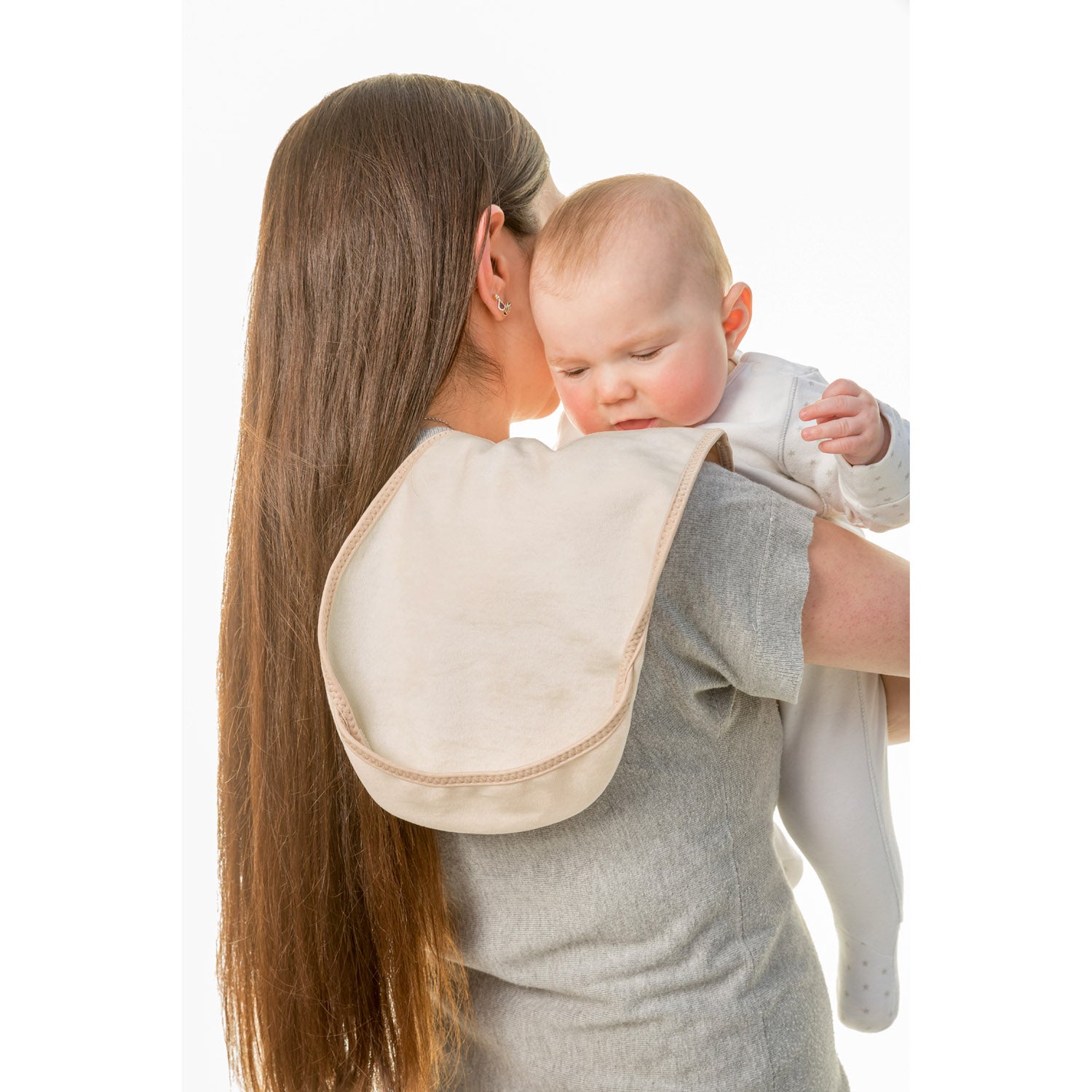 lady with long dark hair wearing a grey t-shirt holding a baby in a white onesie on her shoulder on a Bibetta cream burp cloth